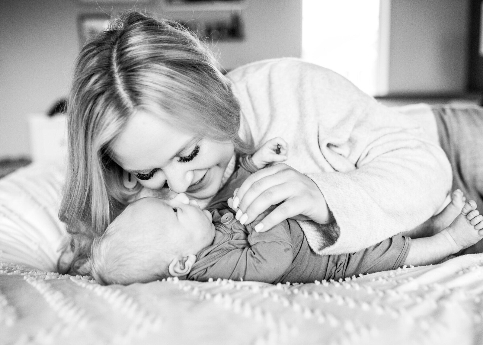 Black & white image of a mom snuggling her newborn son.