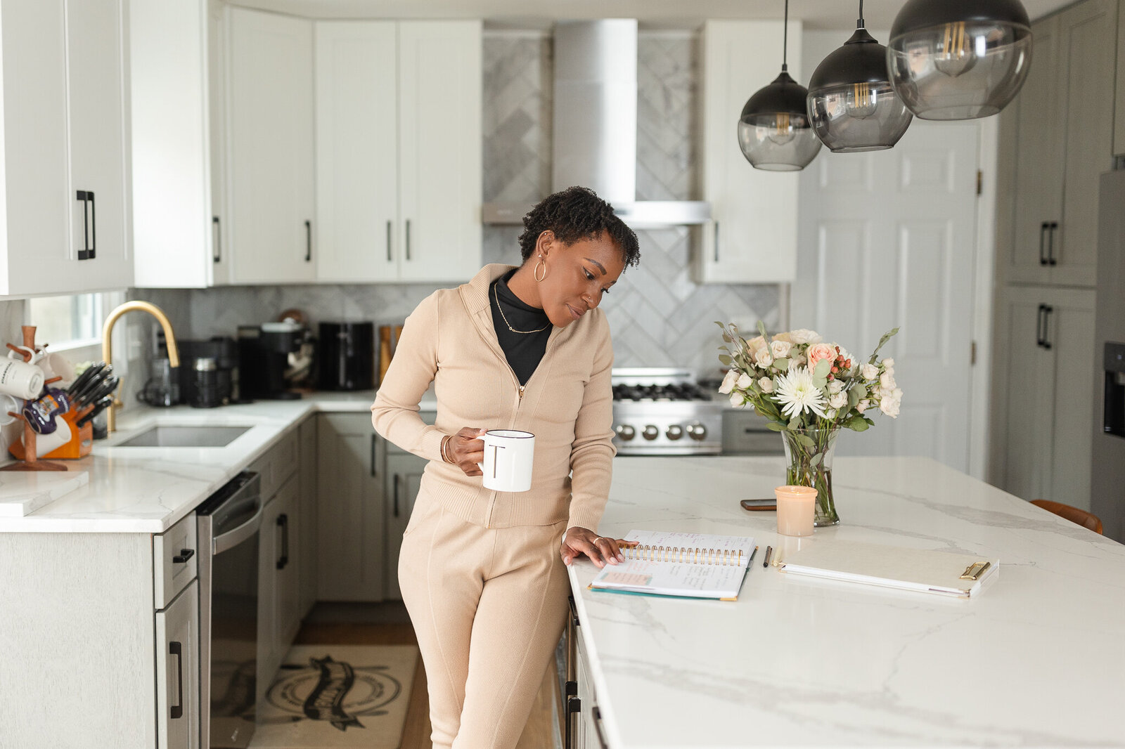 a woman looks over her planner in a bright white kitchen