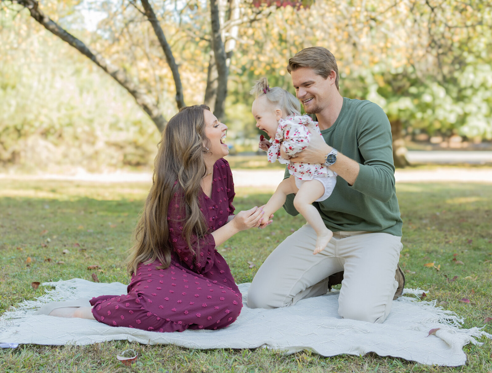 Family sharing joyful moment on white blanket during outdoor photo session near Paramus, NJ