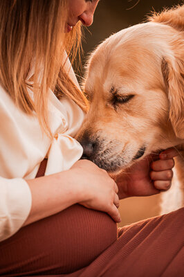 Een aanstaande moeder en haar partner poseren liefdevol met hun hond tijdens een zwangerschapsshoot, een intiem moment vol warmte en verwachting