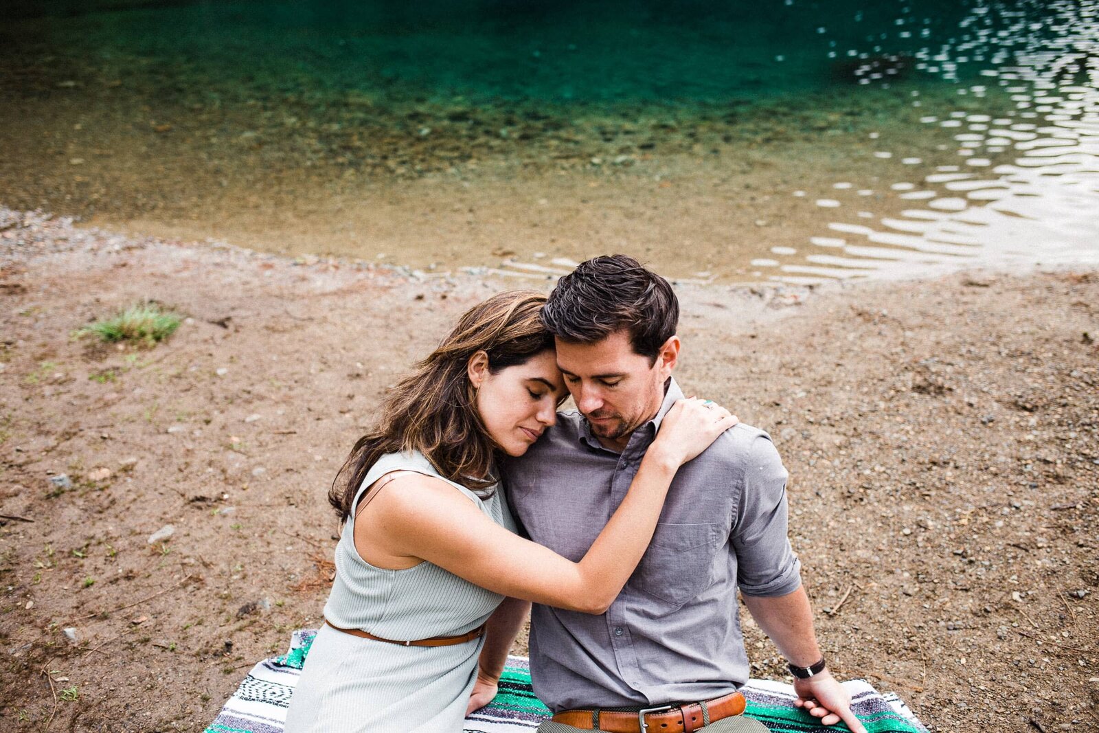 couple cuddling beside a lake