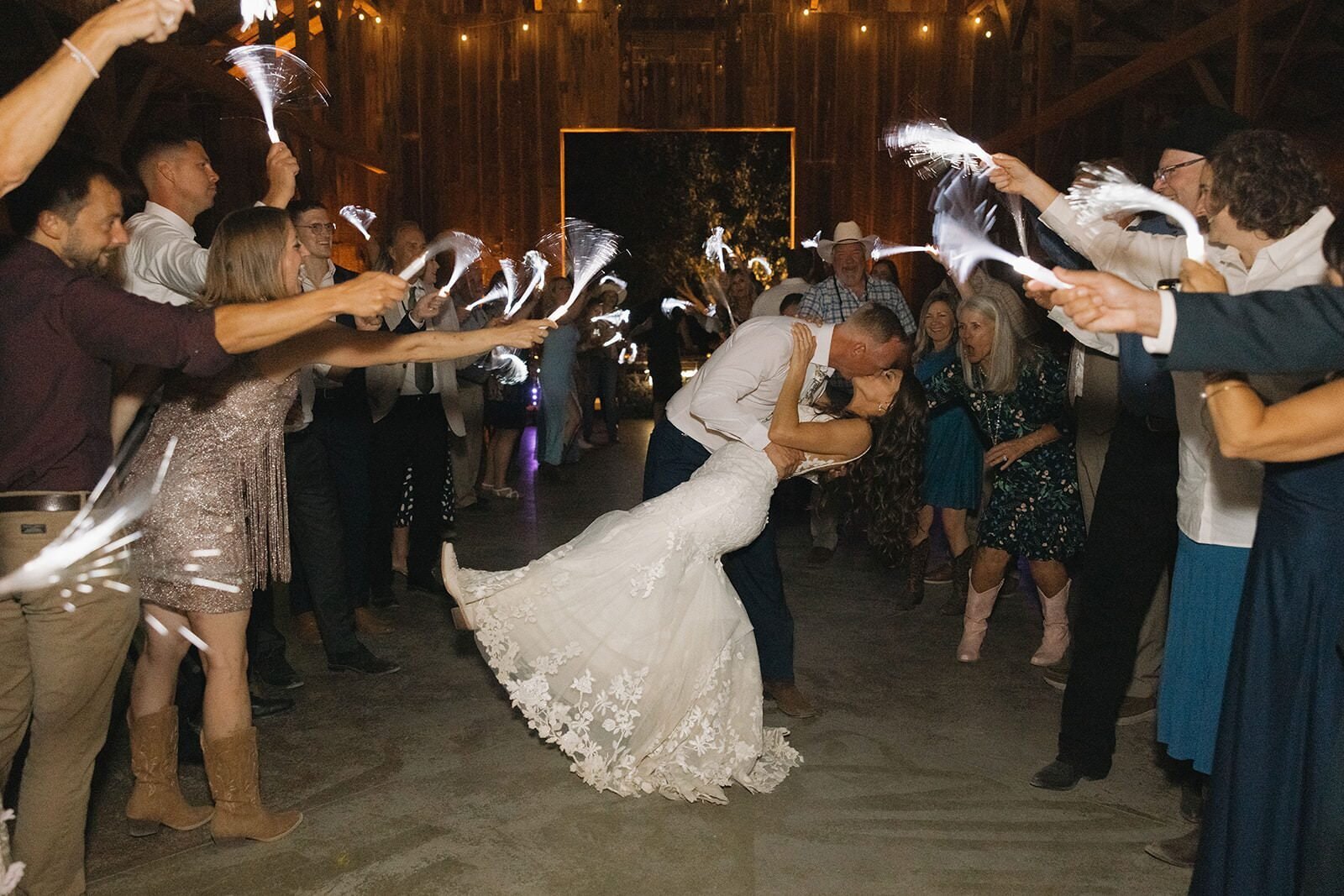 Guests waving light-up wands as the groom dips the bride