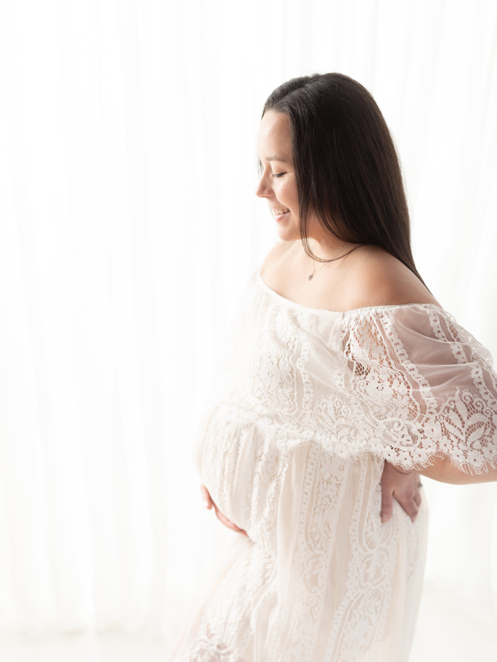 pregnant mother in white lace dress holding belly for maternity photos Cleveland Maternity Photographer
