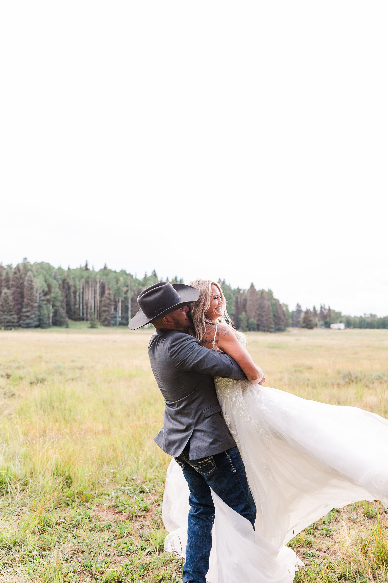 Groom playfully picks up his bride and spins her around during their sunset portraits at their Arrow Head Lodge Wedding - 