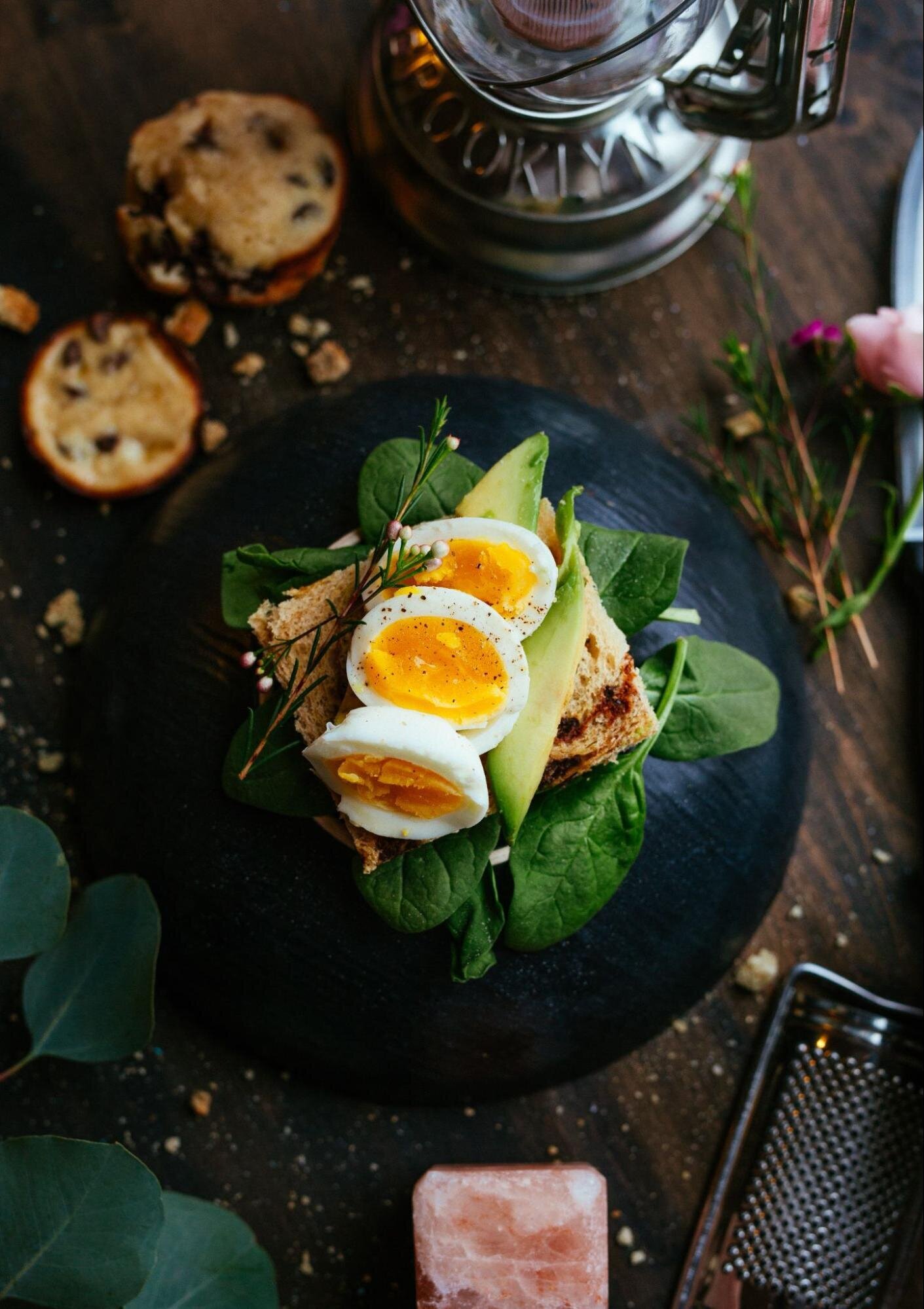 Image: three boiled egg halves on avocado toast resting on a bed of spinach