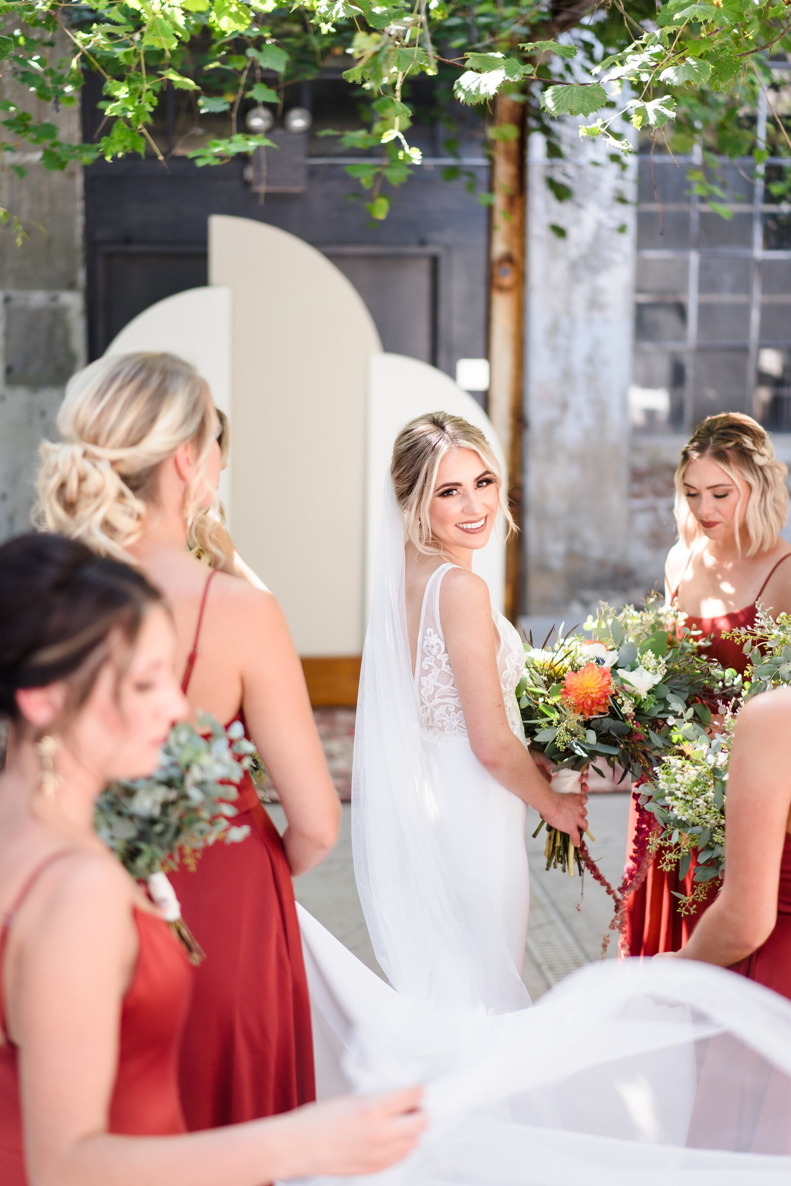 Bridesmaids hold onto the bride's train as she smiles back at the camera
