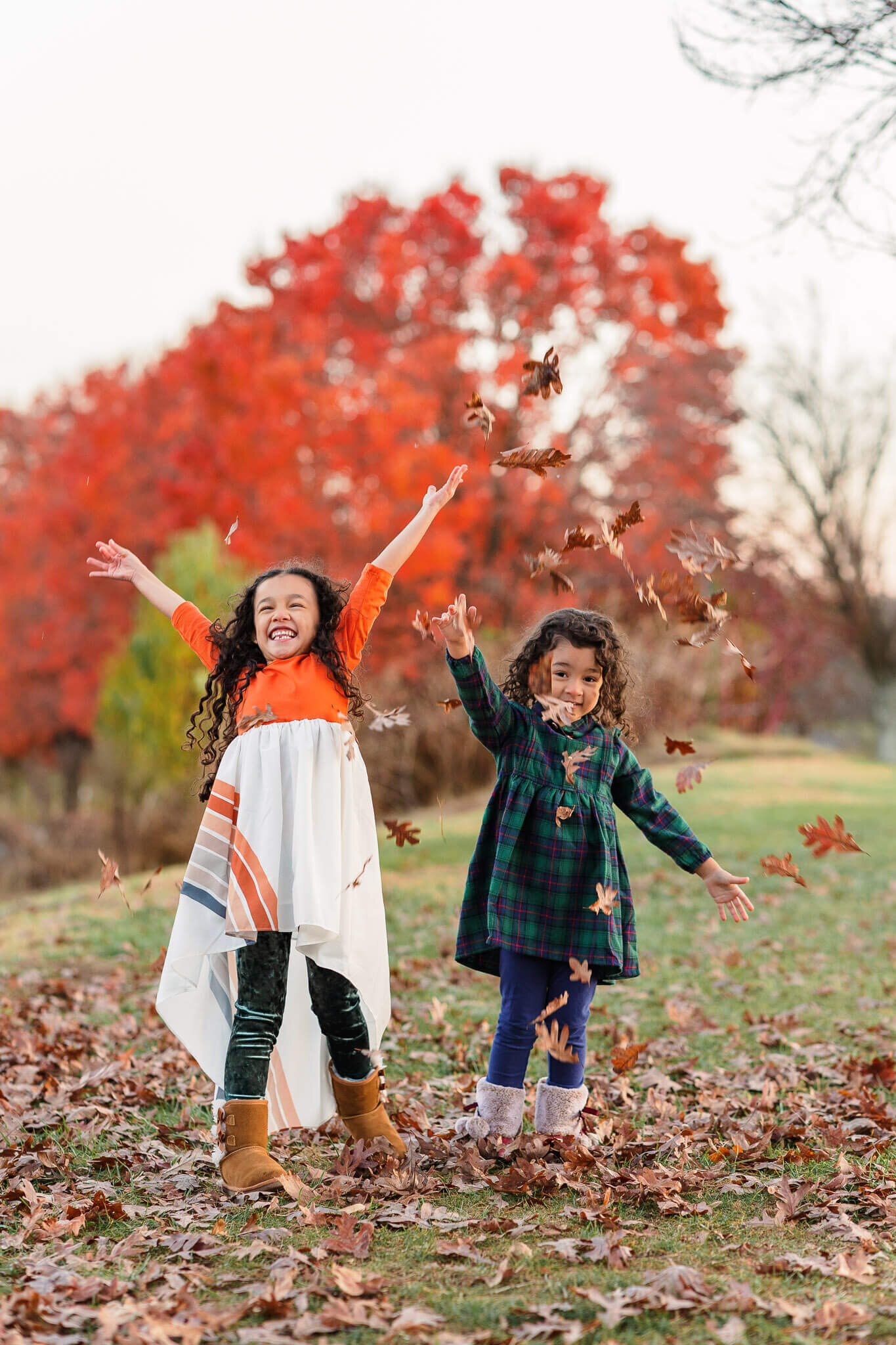 Two sisters throwing leaves in the air together