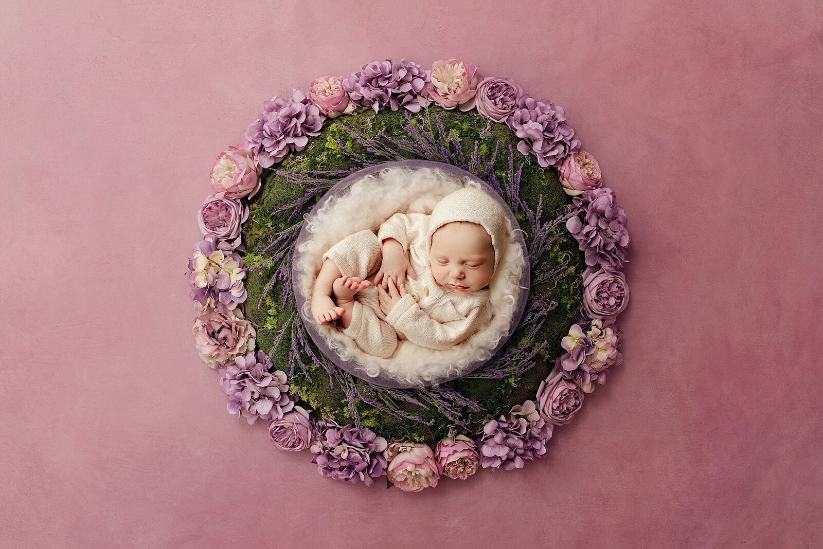 baby girl posed on a bowl with pink and purple glowers