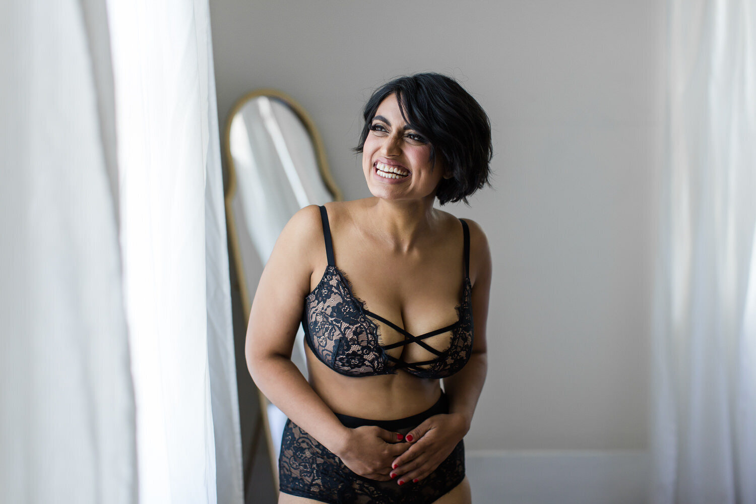 joyful confident boudoir photo of woman in lingerie