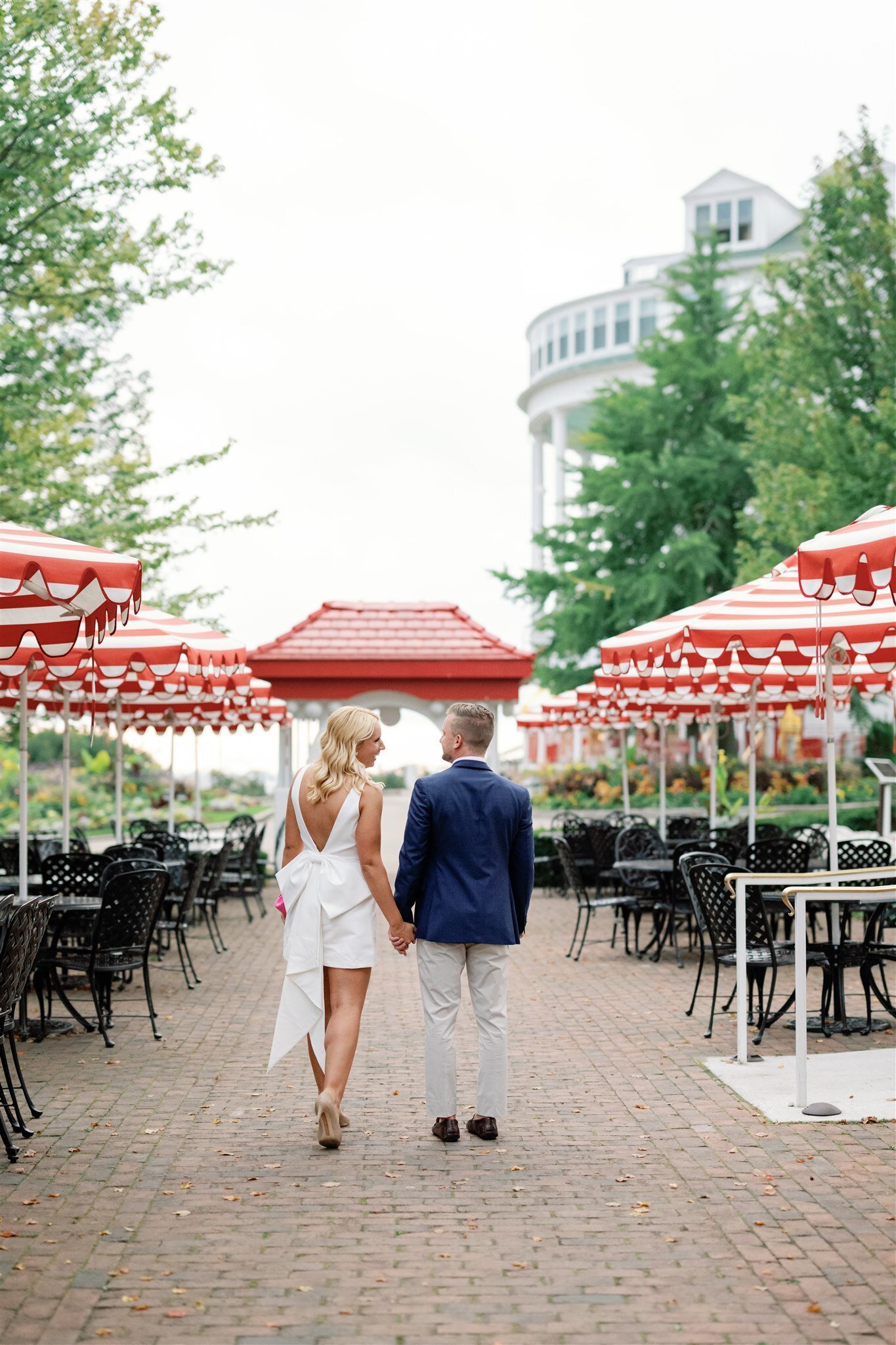 Iconic red and white umbrellas at the jockey club surrounding a couple as they walk toward the Grand Hotel