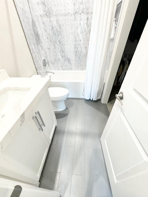 Residential home design and renovation featuring a main bedroom's private white bathroom with a clean, elegant aesthetic and modern fixtures.
