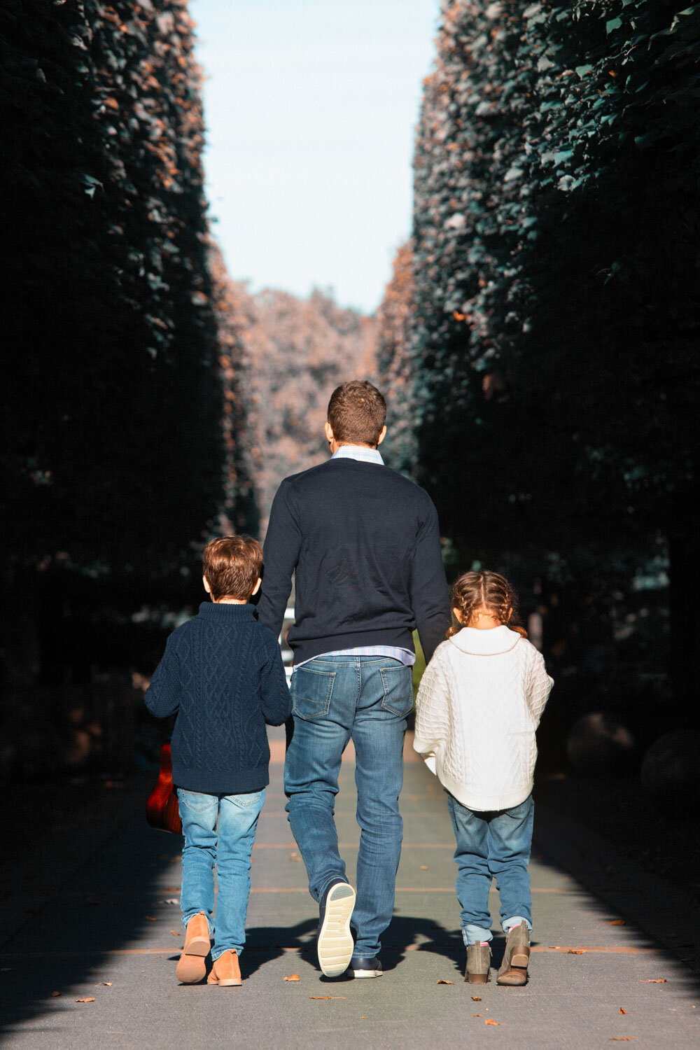 A man and two children are walking down a path holding hands