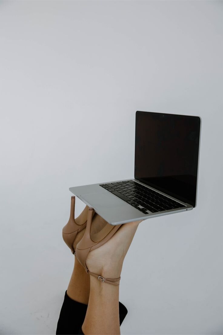 Woman balancing a laptop with her feet while lying down, representing playful independence and the freedom to access The Clair Academy’s digital dating and self-growth resources anytime, anywhere.
