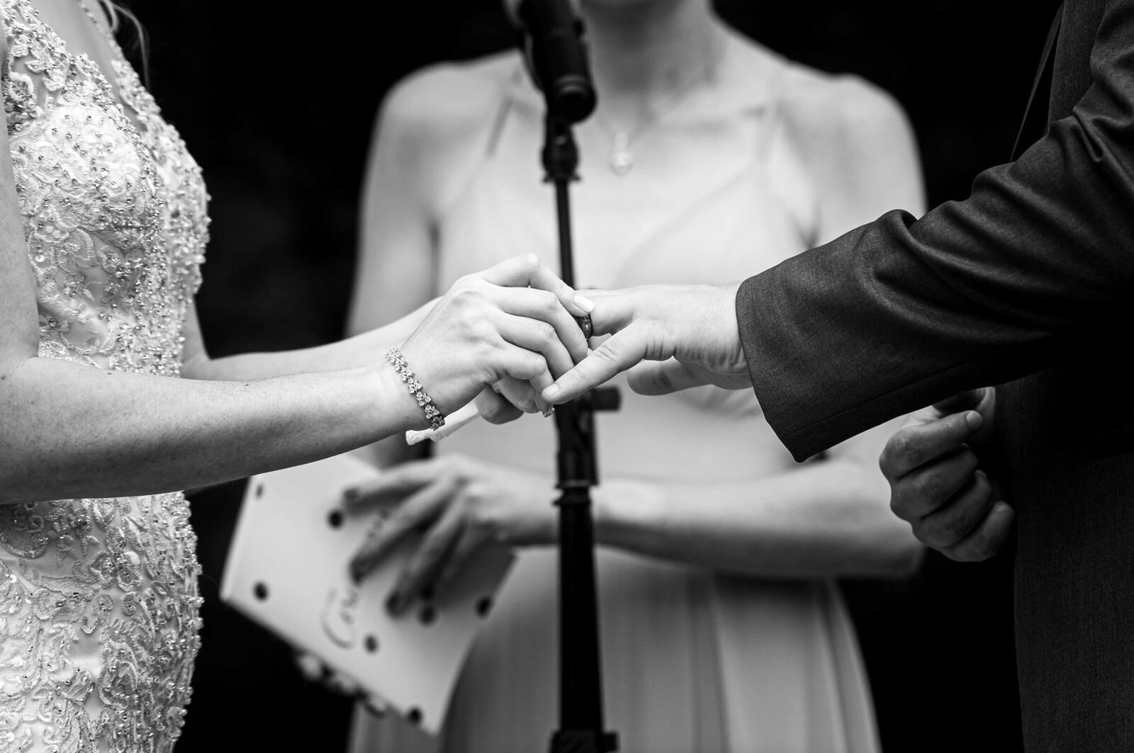 Close-up view of a bride, putting on her grooms wedding band during their ceremony at the English manor in Ocean NJ