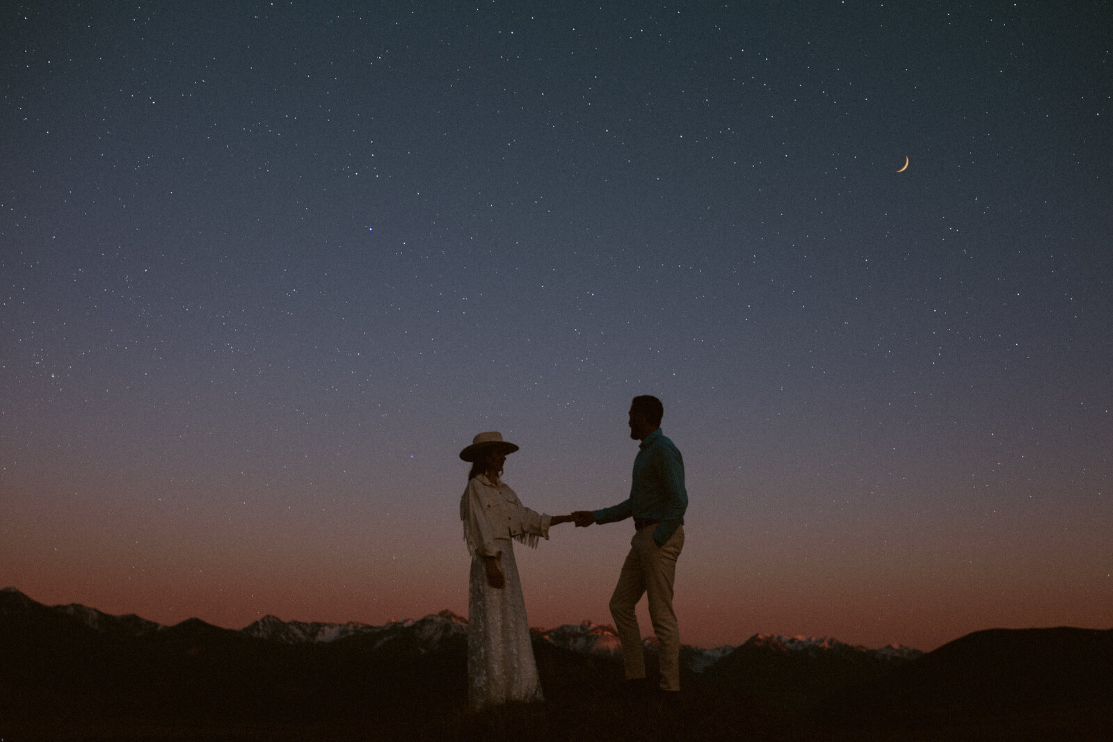 Couple holds hands under the night sky