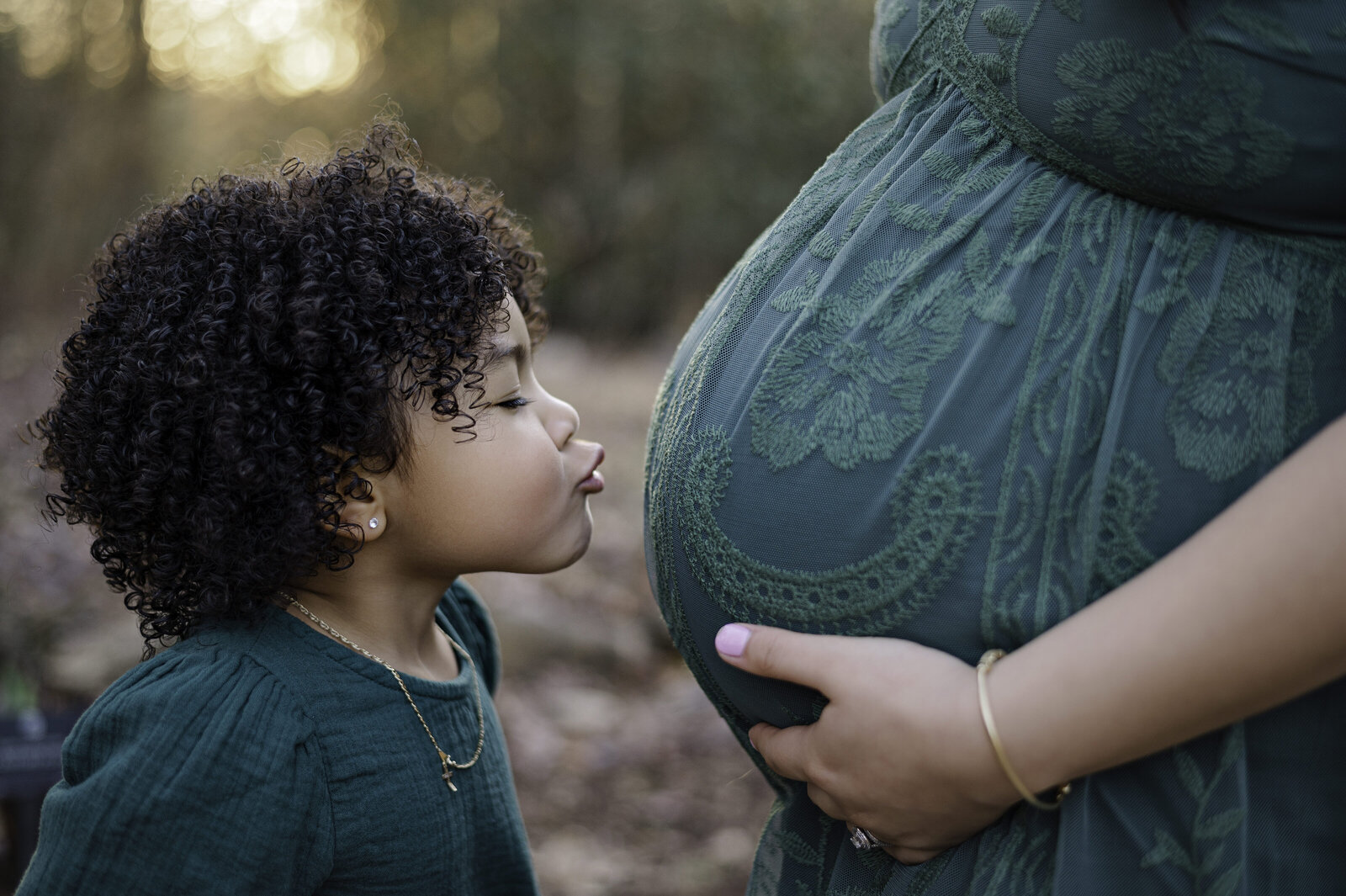 Little girl leans in to kiss her mothers pregnant belly. Athens maternity photo by Amanda Touchstone