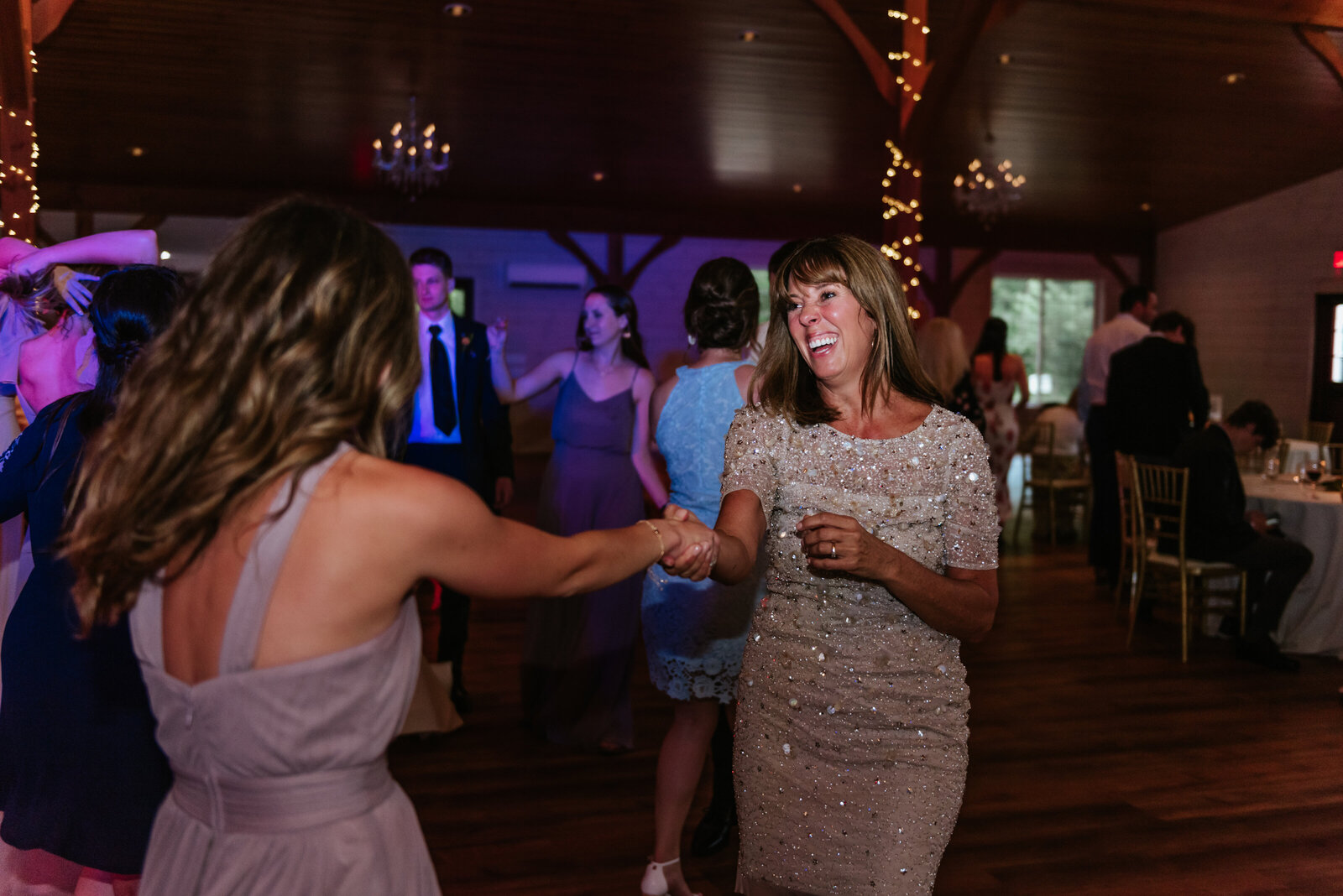 Two women laugh while dancing at a wedding reception