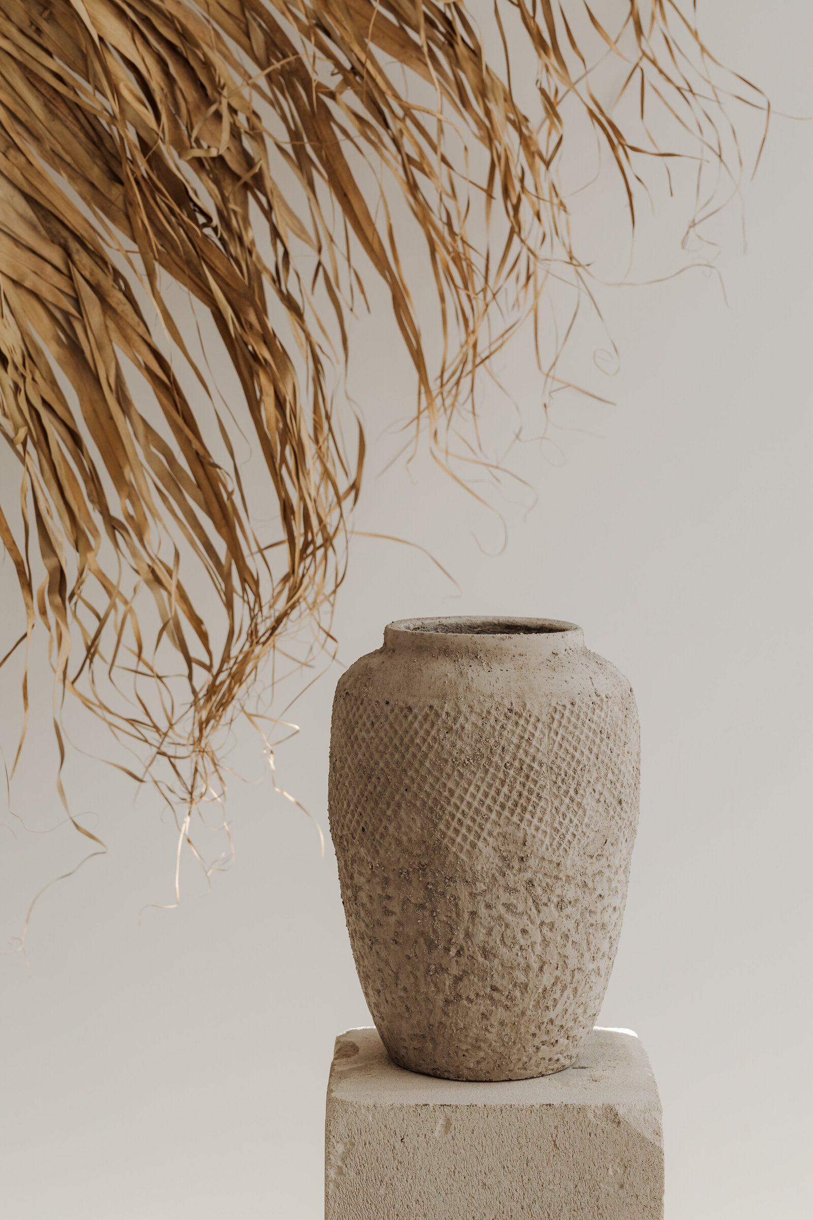 kaboompics_a-textured-clay-vase-placed-on-a-minimal-stone-pedestal-creating-a-natural-earthy-aesthetic-36996