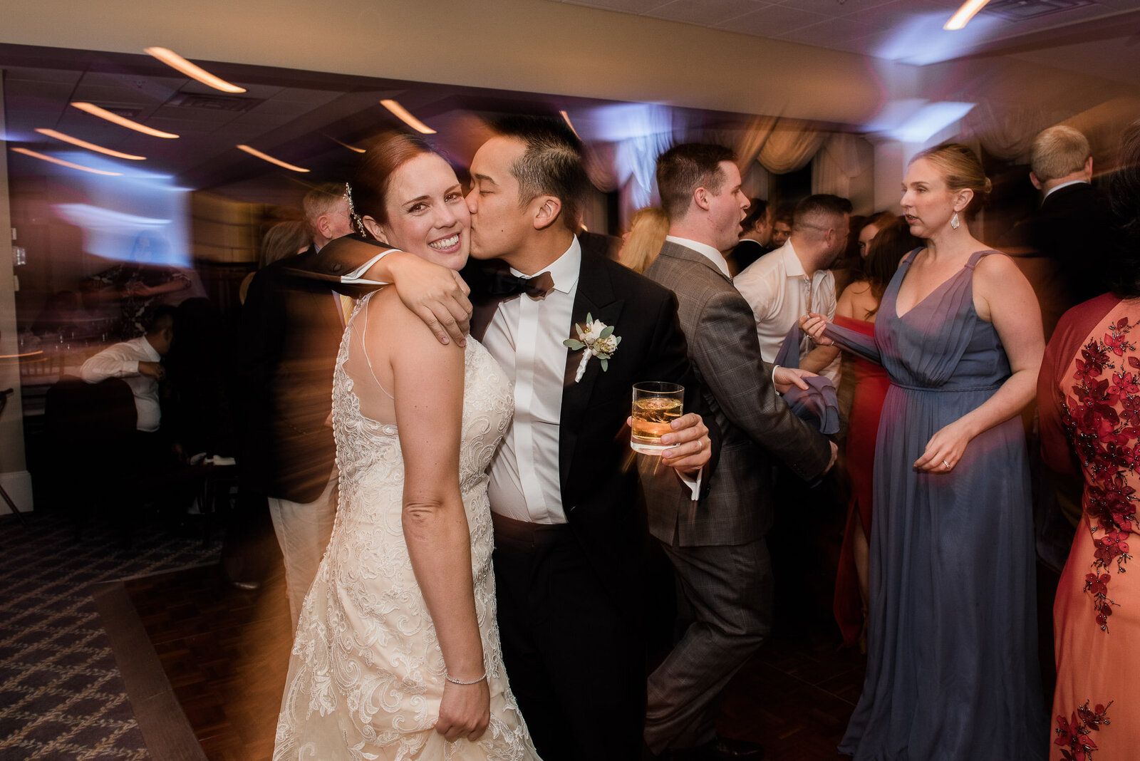 groom kisses bride while dancing with light streams