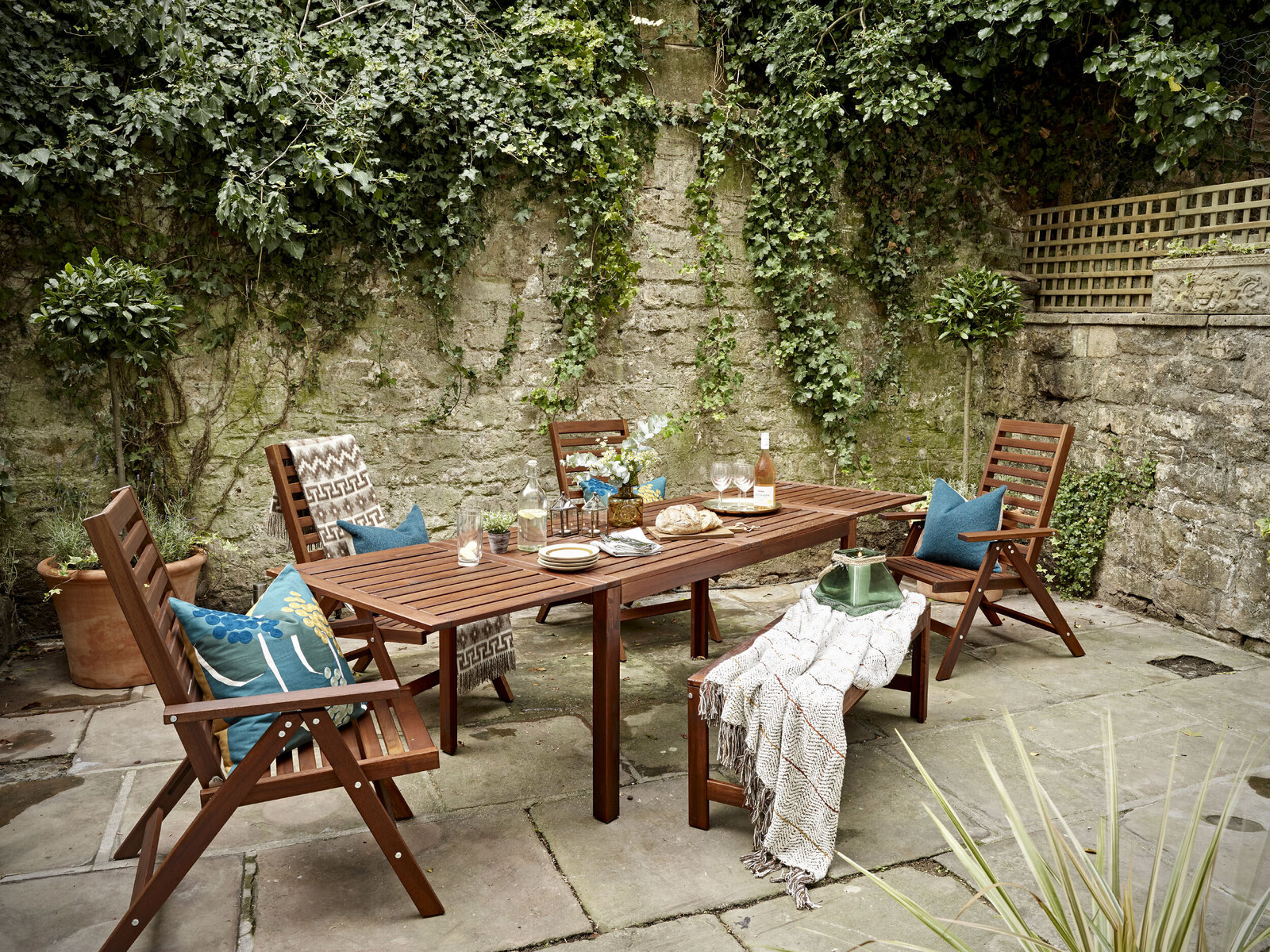 styled garden patio with dark wood table and teal accent pillows