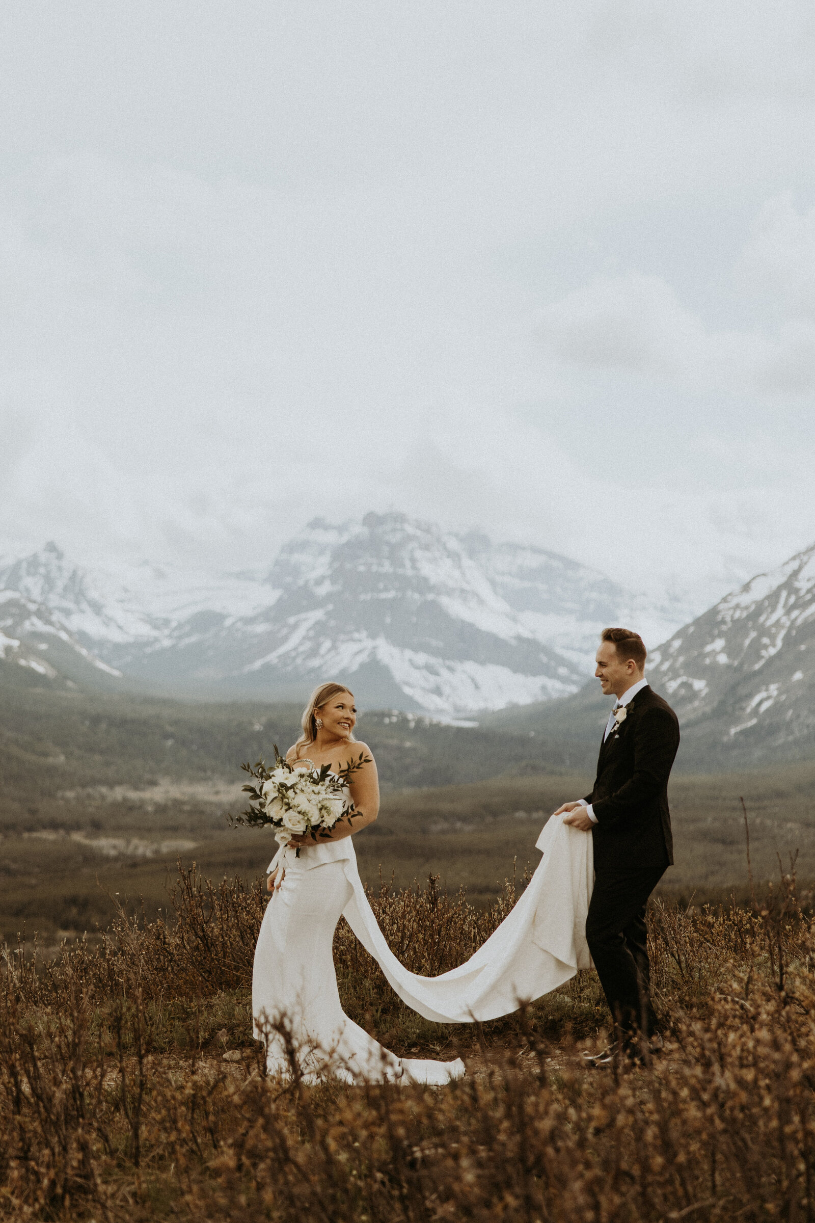 couple walking together in field in front of montana mountains