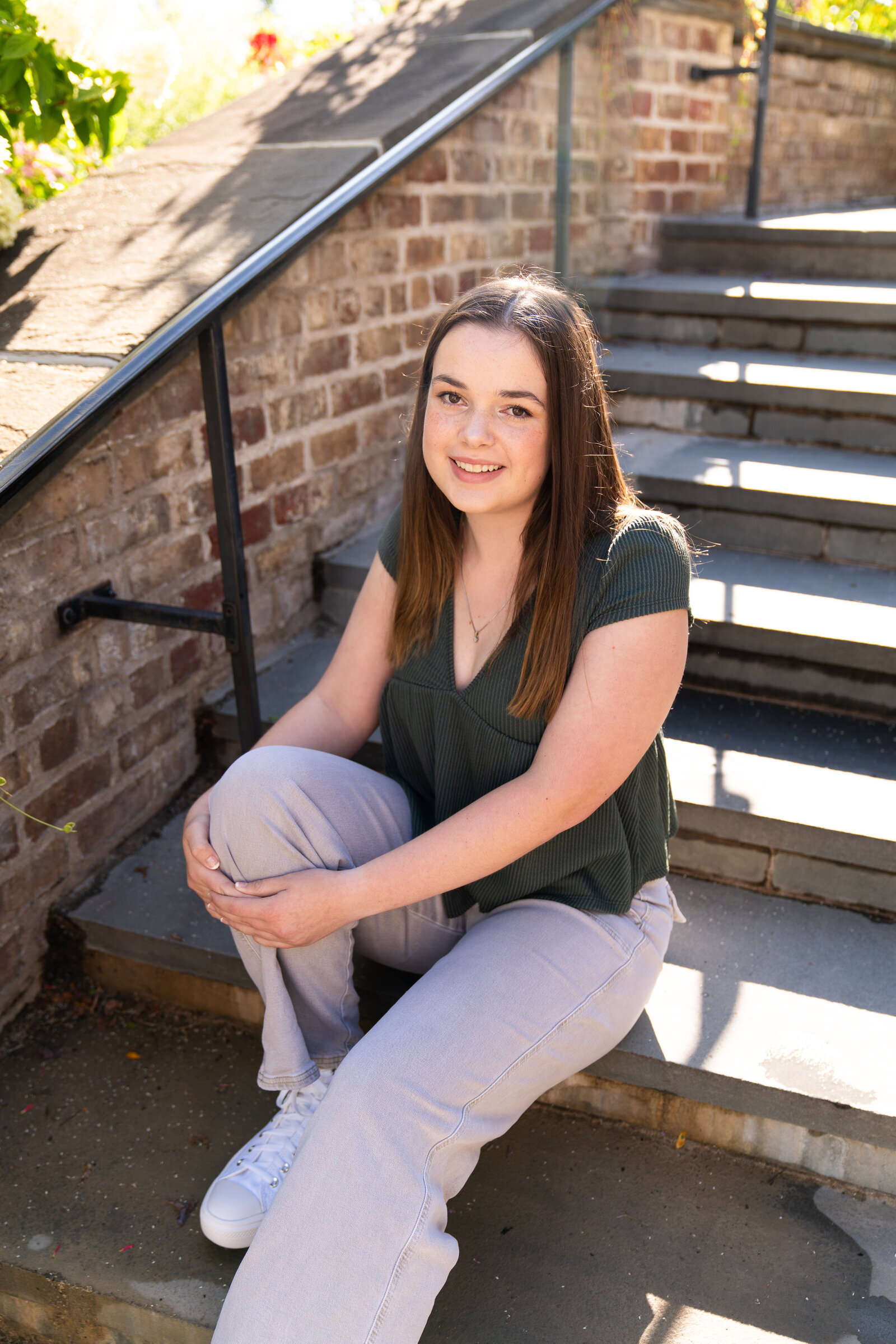 Girl sits on steps for her senior photo shoot at the Minnesota Landscape Arboretum in Chaska, Minnesota.