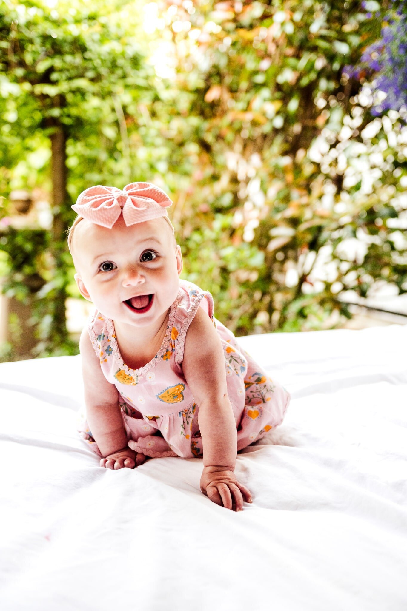baby in a pink dress with bow smiling