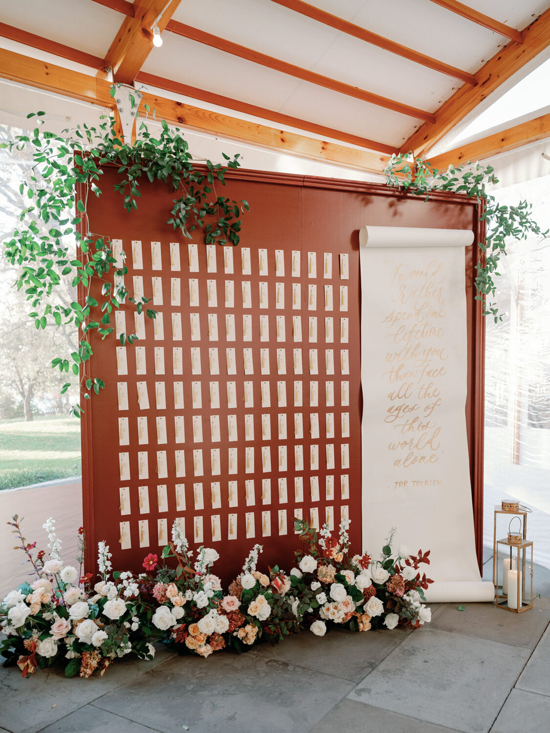 Wall of names tags for guests at a luxury wedding in upstate New York. A large white scroll with calligraphy on it shares the frame.