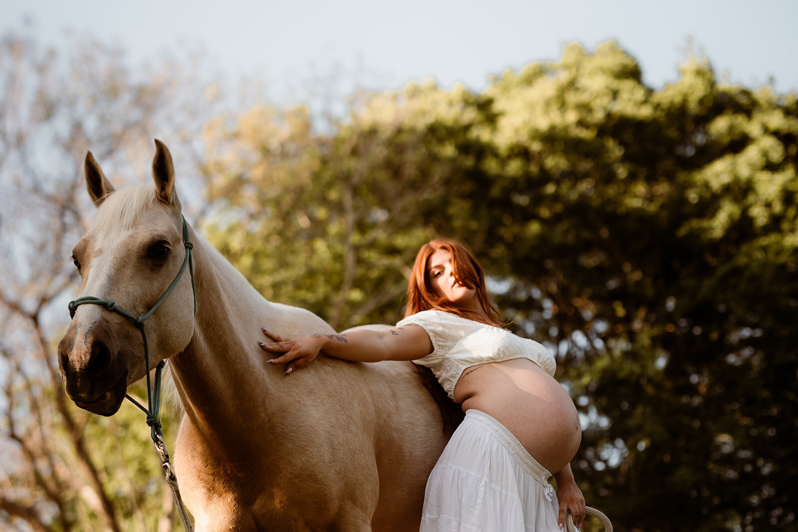 Mother leaning against horse in createive maternity photography session