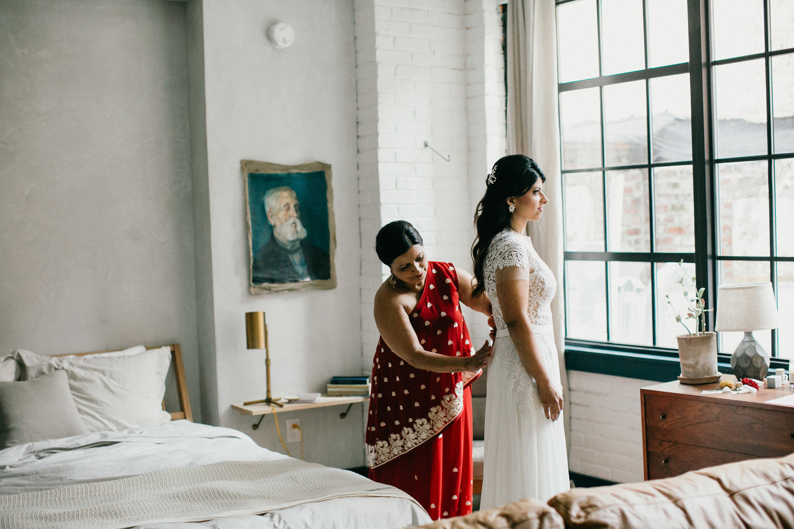 Beautiful natural light photograph of the bride and her mother helping with the finishing touches to her bridal look.