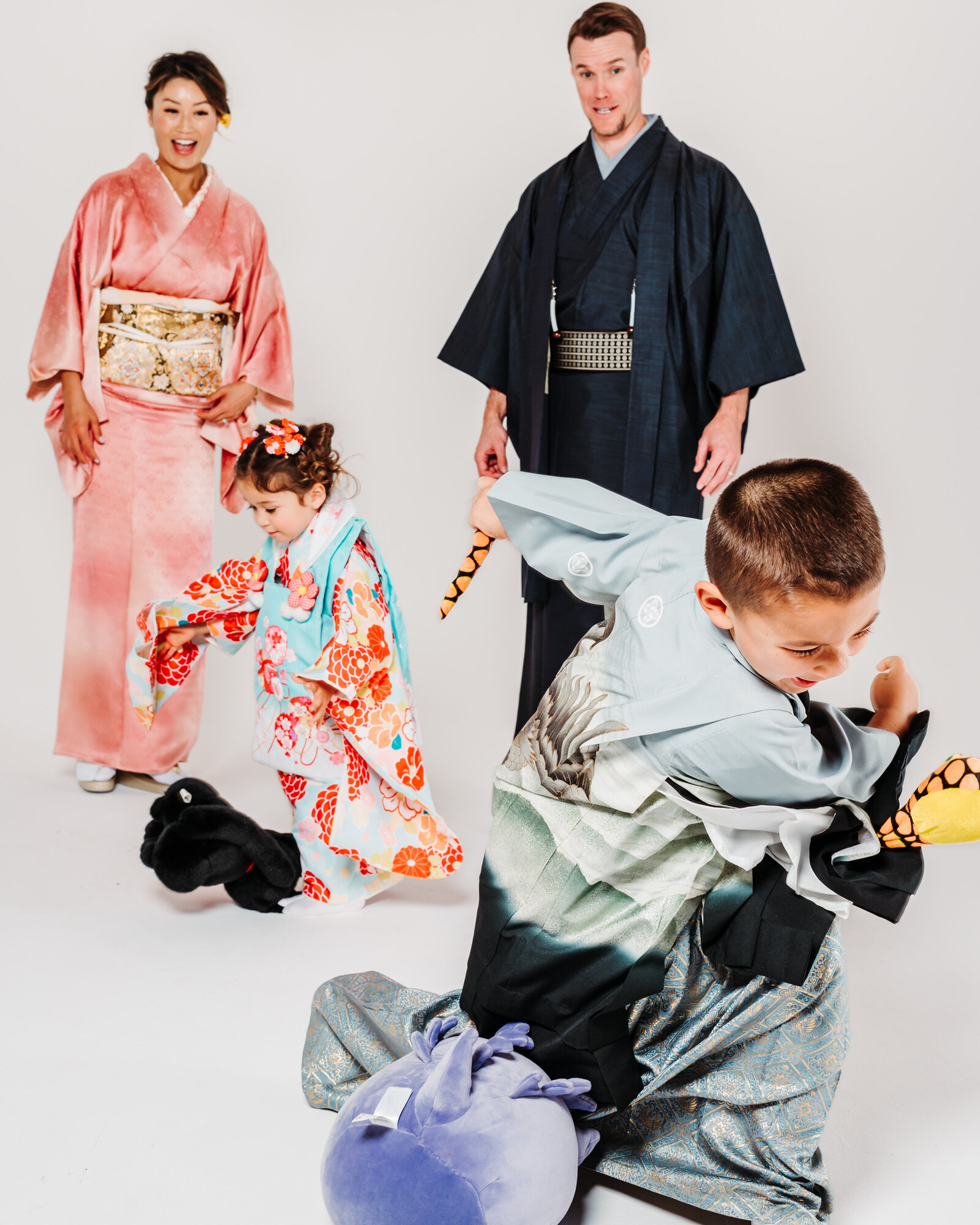 Family in kimono during Shichi-Go-San photoshoot, children playing with toys while parents smile | 七五三 家族写真 遊ぶ子供たちと笑顔の両親