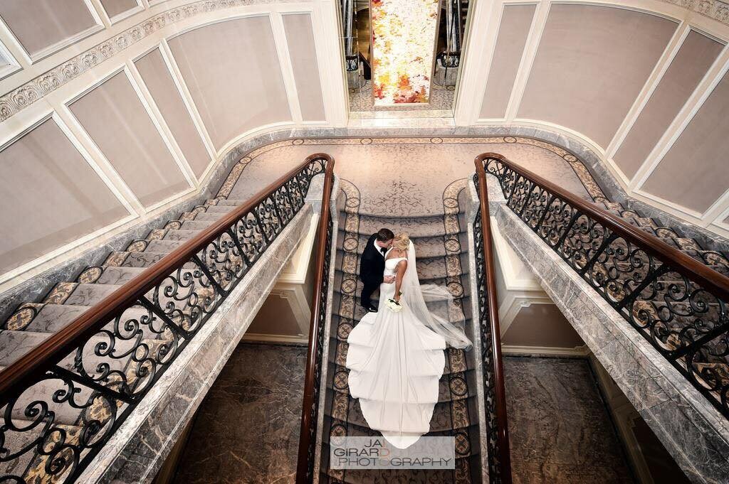 Bride and groom embrace on grand staircase