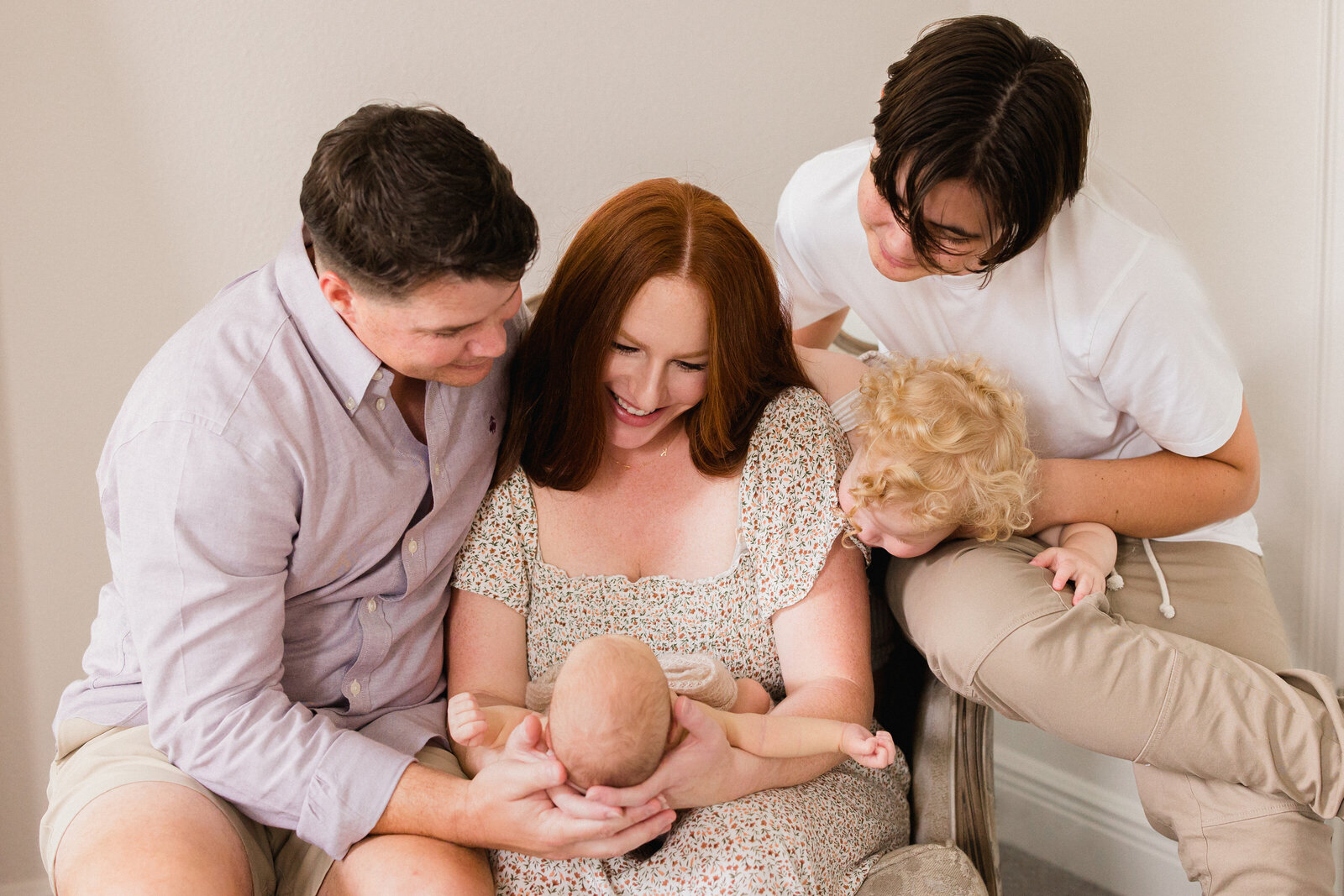 A newborn is the center of attention as mom, dad, and both siblings all gather around him to stare