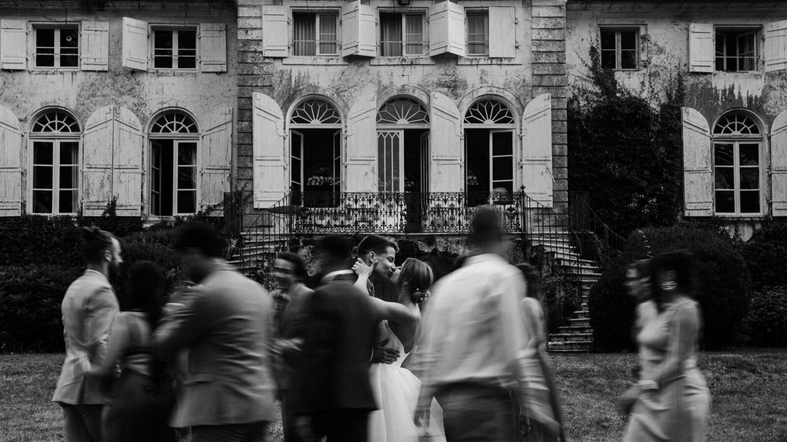 Amazing picture of a couple kissing at their wedding while family and friends move around them