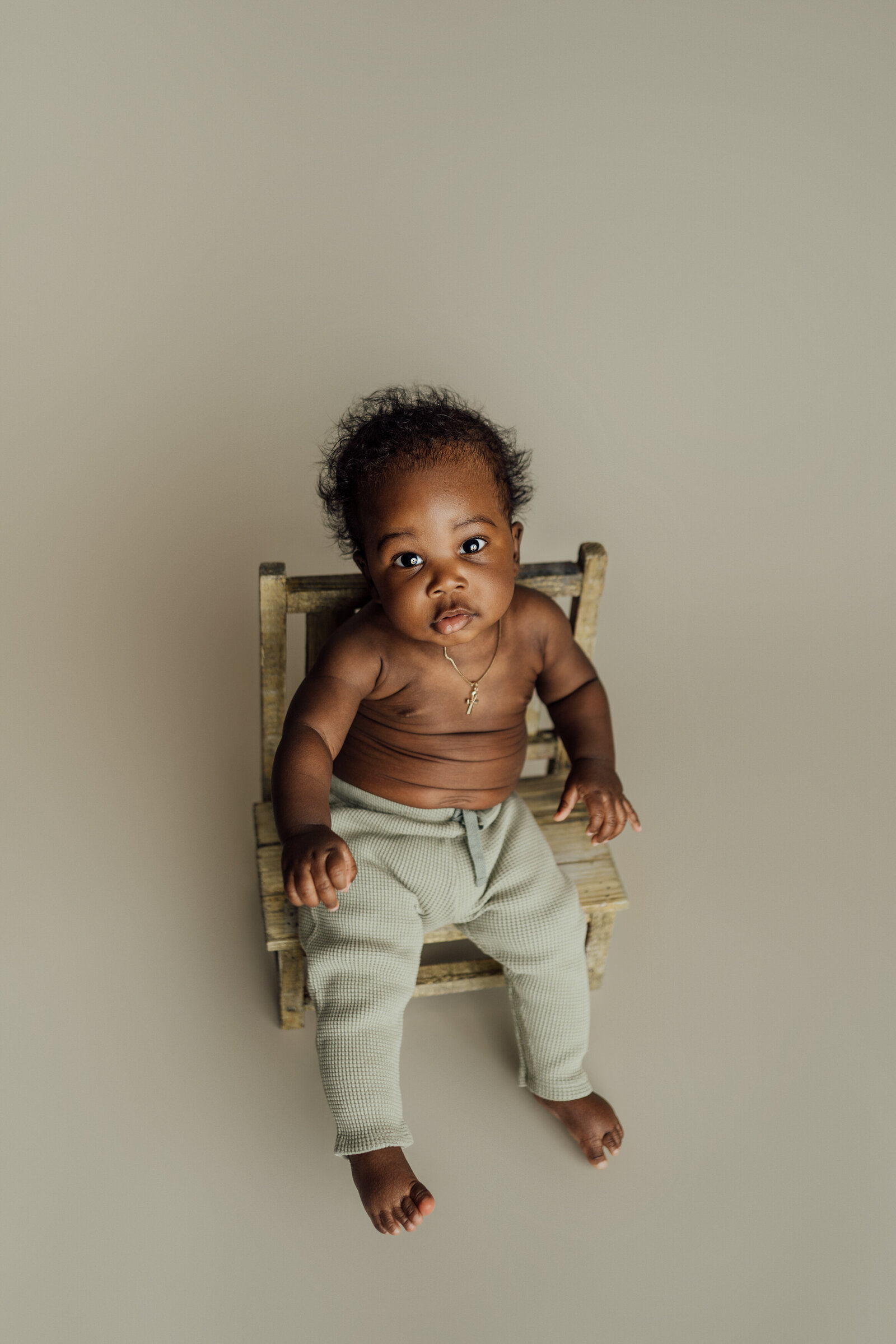 6 month old boy poses on chair for milestone photography session in Tampa