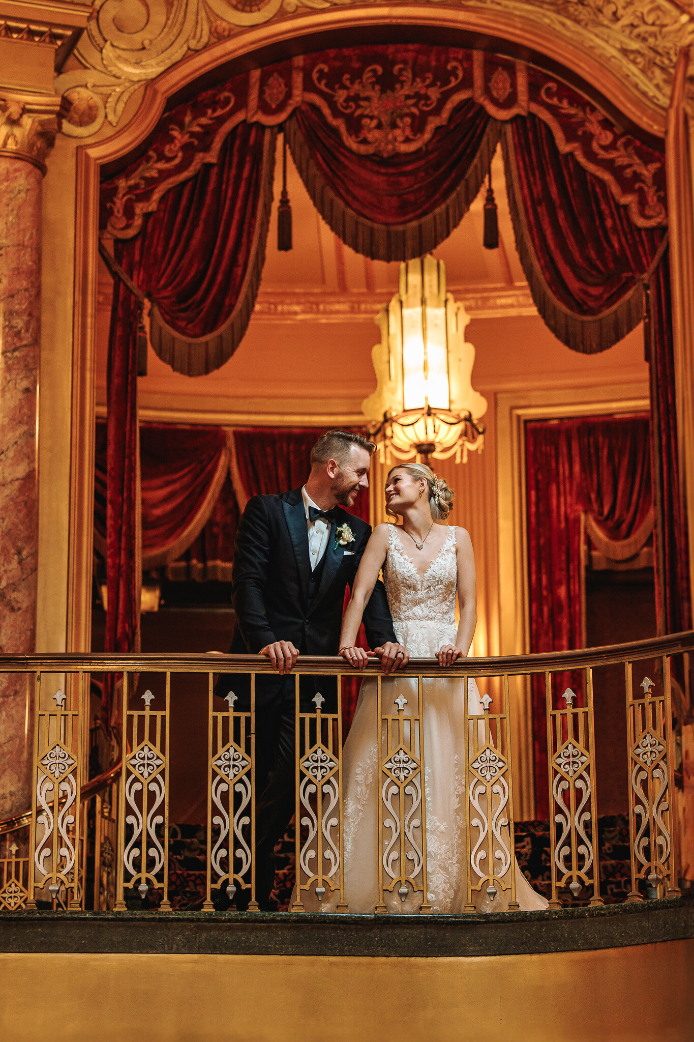 A bride and groom gaze into each other eyes on a balcony of the historic Warner Theater in Erie PA