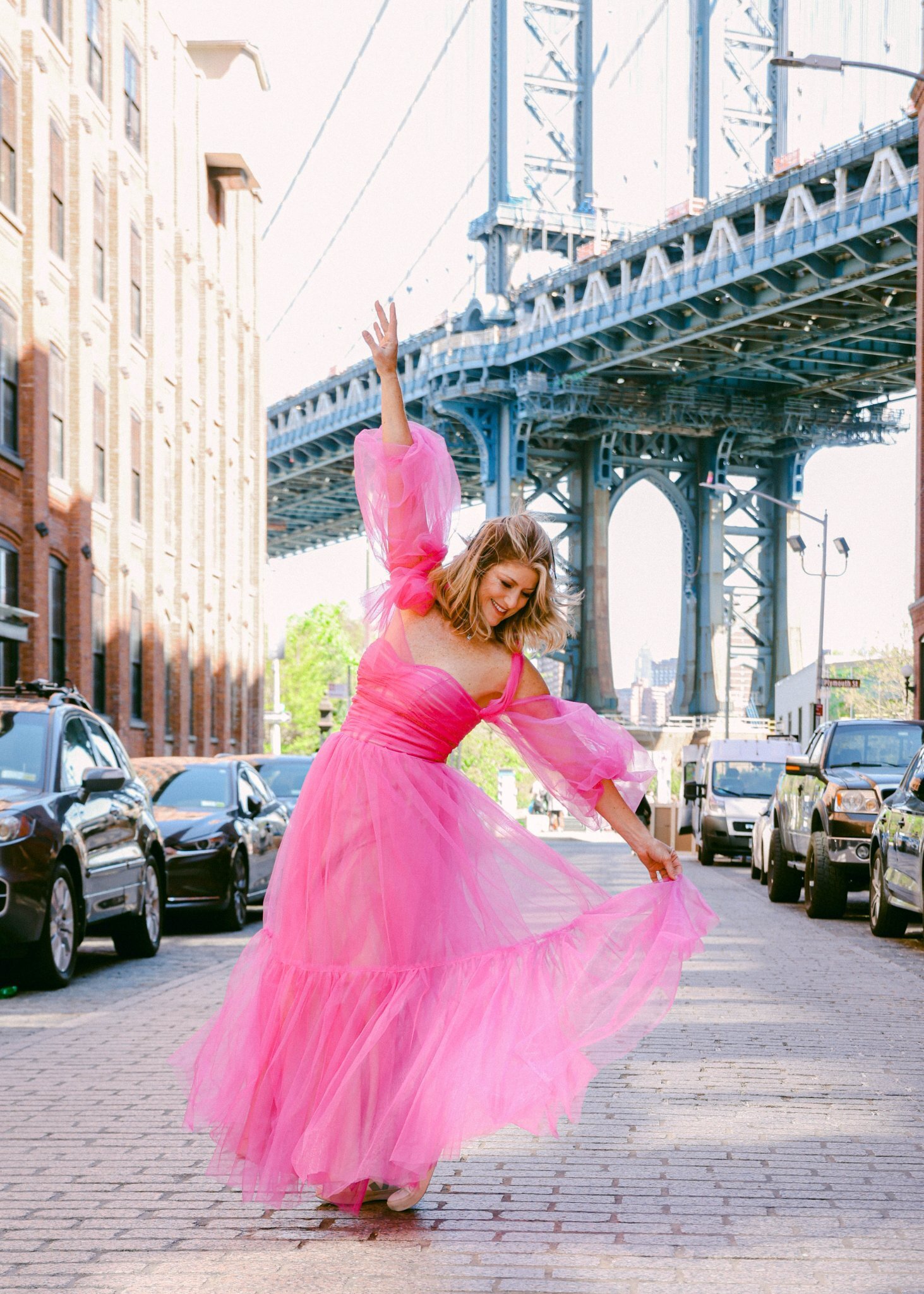 Branding Photographer Chelsea Loren photographing Gayle Dawn in pink tulle dress under the Manhattan Bridge in Dumbo Brooklyn New York City bachelorette party.