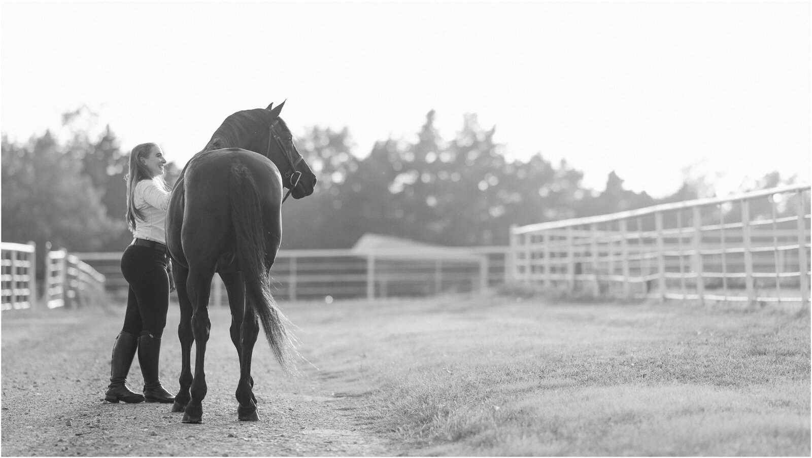 A black and white portrait of an adult amateur hunter rider and her retired black warmblood gelding at their boarding barn in Stillwater Oklahoma