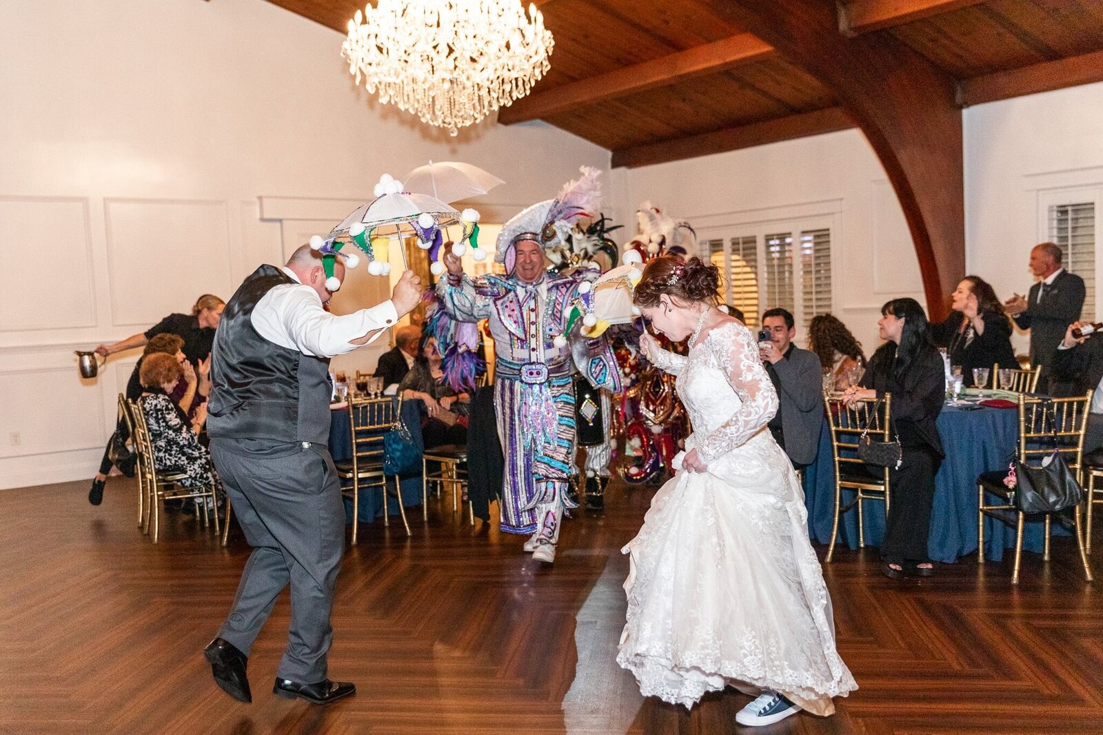 A wedding reception with a Mummers surprise – The bride and groom dance joyfully as their reception is transformed into 2 street when the Mummers arrive in elaborate, feathered costumes. Their Philadelphia energy and history brings a lively burst of color and tradition. The bride’s lace wedding dress sways as she joins in the celebration, while the groom waves a decorated umbrella in the air