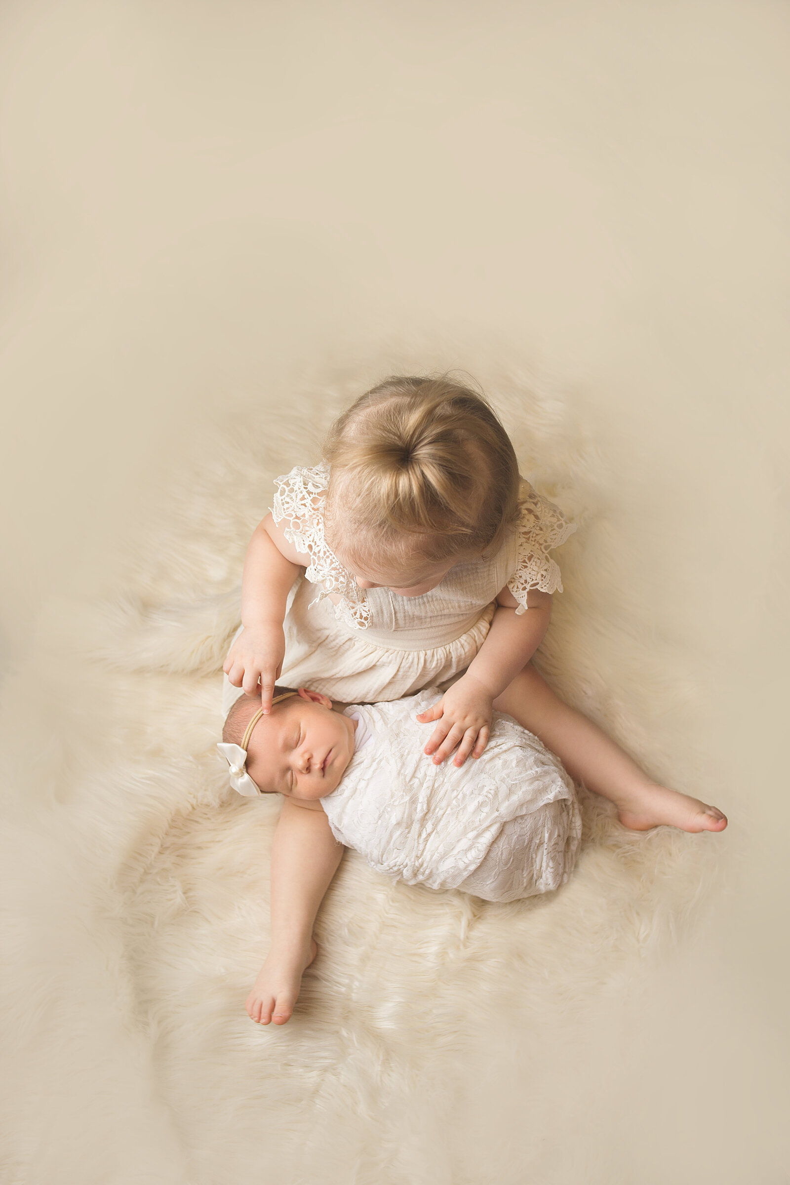 Big sister sitting holding new baby during newborn photoshoot with Nashville, TN newborn photographer