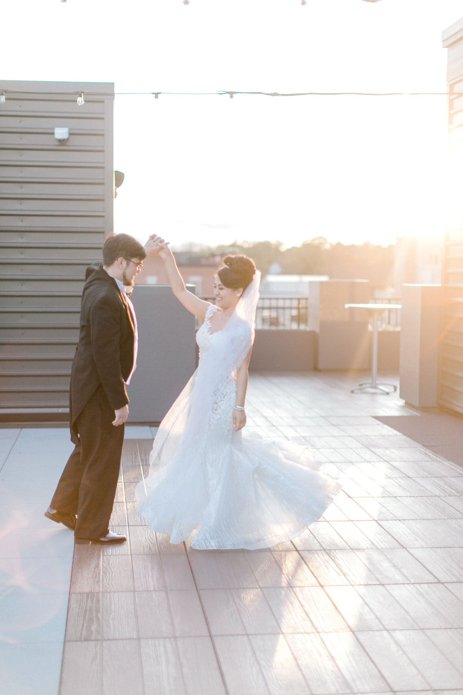 Husband and bride dancing at sunset on rooftop