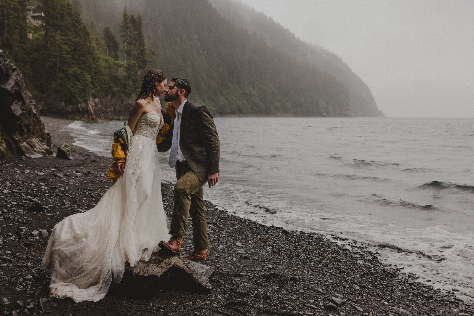 A couple wears their matching hiking backpacks while dressed in their wedding day attire
