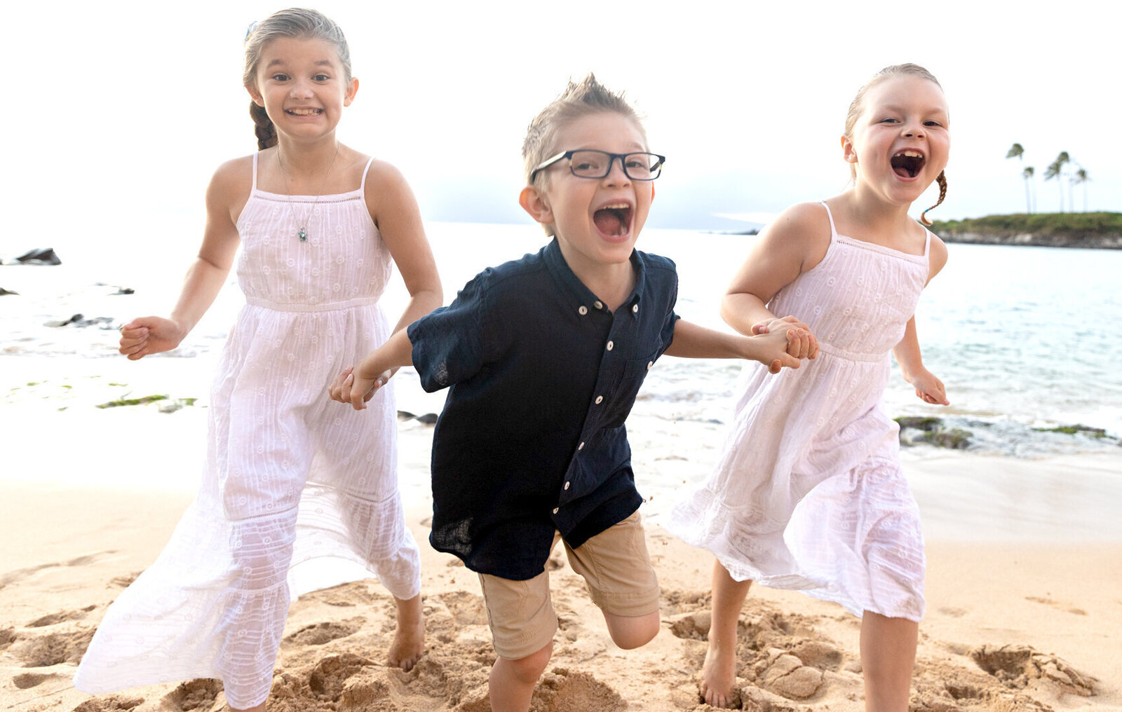 three happy children running towards the camera on their family portrait in Waikiki
