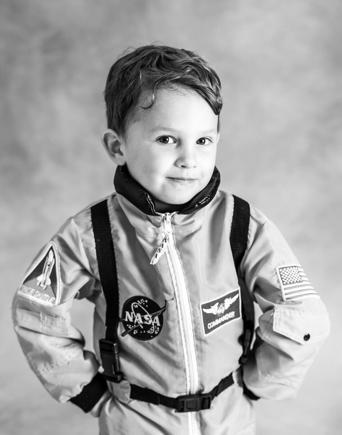 A child in a NASA suit poses with hands on their hips.
