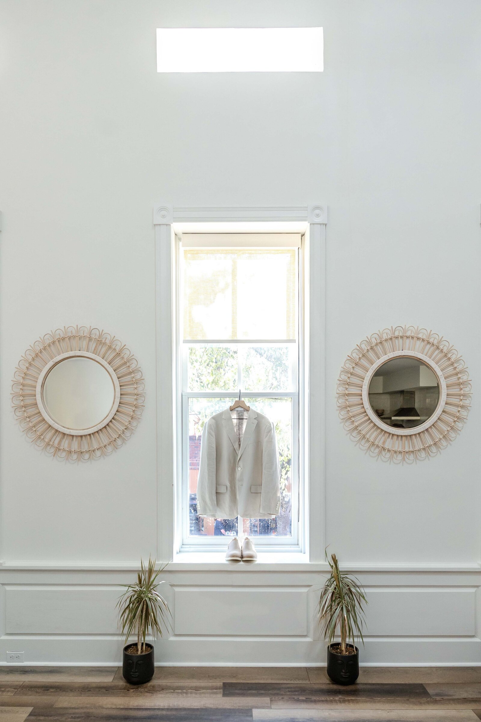 A groom’s light tan suit and shoes elegantly displayed in front of a bright window at a Wilmington, NC wedding venue, highlighting a sophisticated and timeless style.