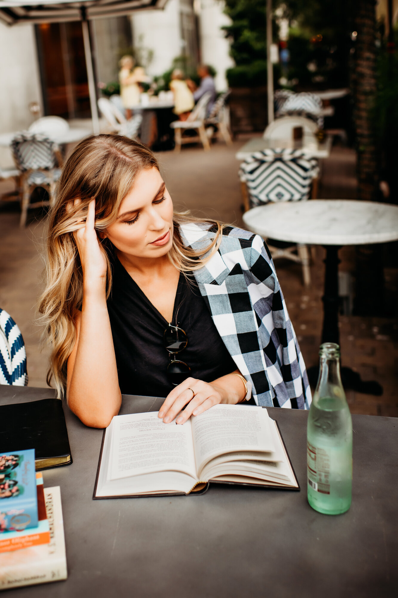 Branding Photographer, a woman reads a book at a cafe table with a sparkling water bottle beside her