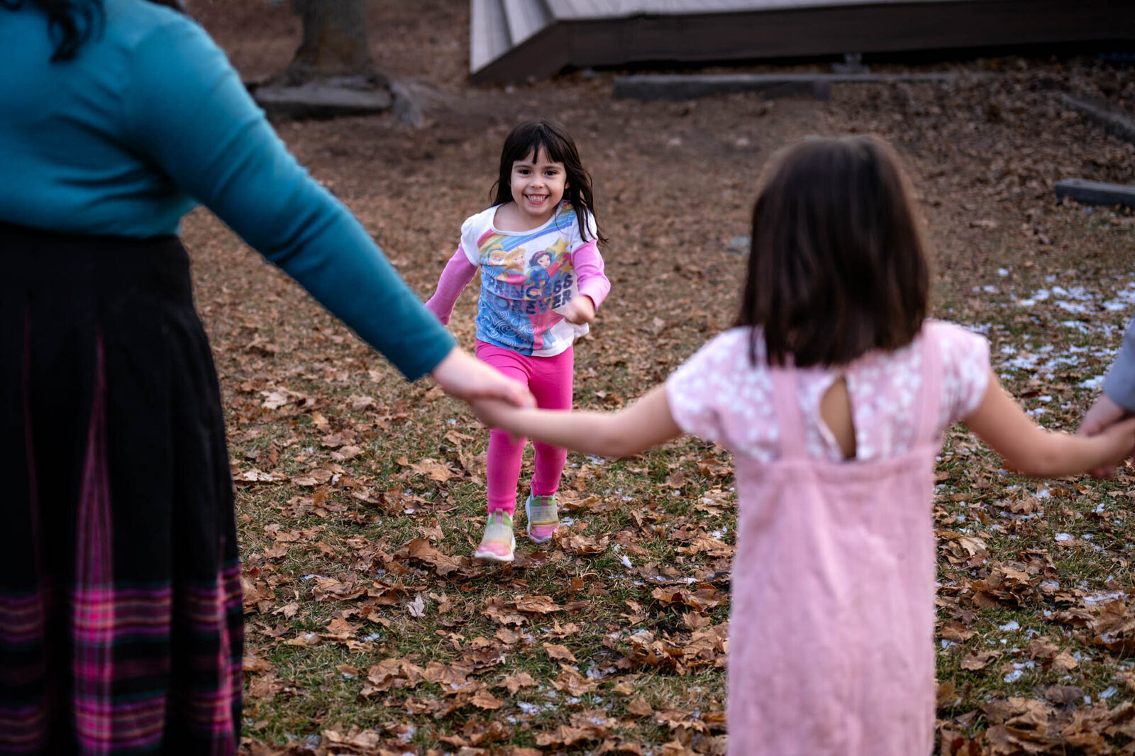 Youngest daughter laughs during a game of red rover with family during photoshoot