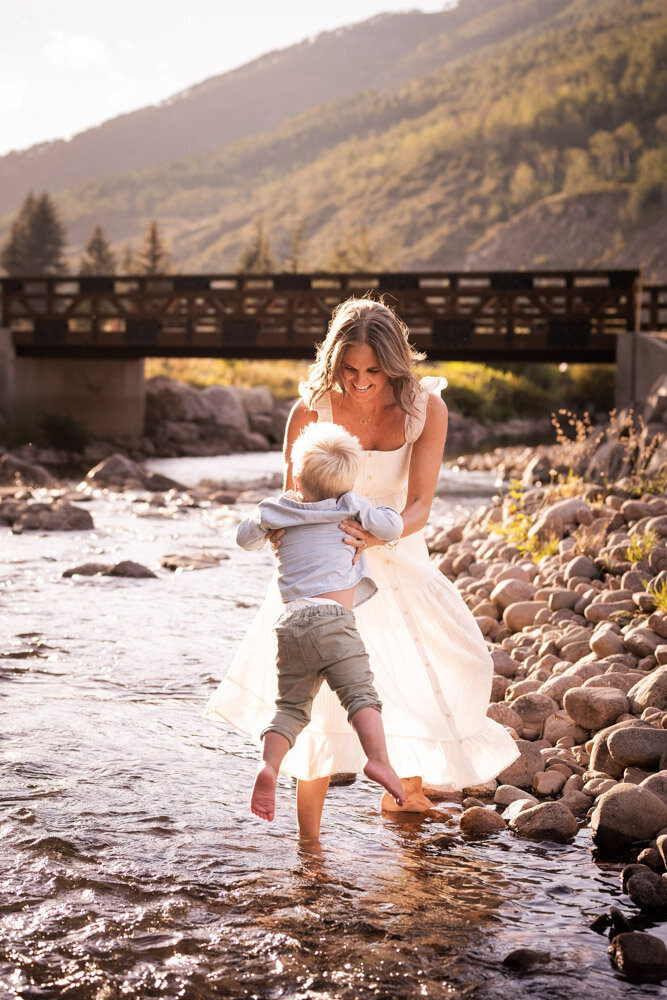 A mom puts her son's toes in the river