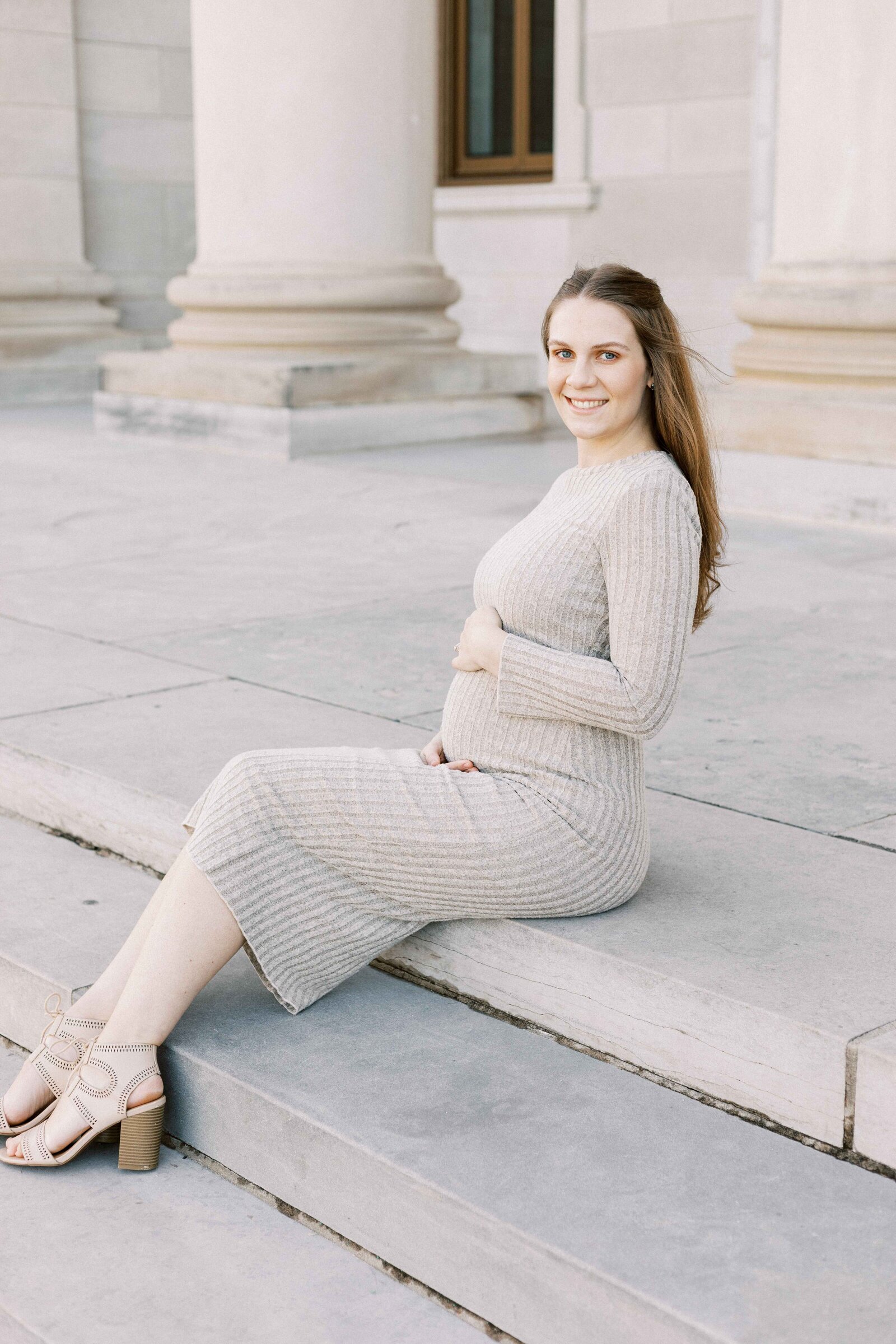 mom sitting on steps and holding baby bump during peoria illinois maternity photos 