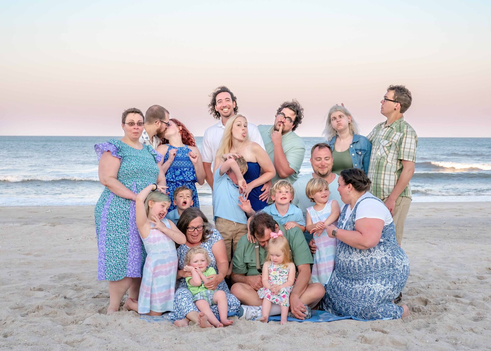 A lively family poses on the sands of Ocean Isle Beach, dressed in colorful and patterned outfits. Their playful expressions and the pastel evening sky highlight the joy of a family reunion. Perfect for artistic family photography in Wilmington, NC, capturing candid family interactions.